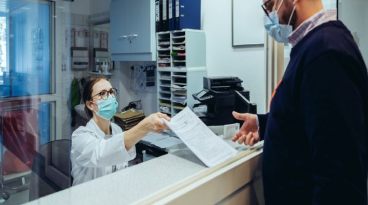 Two individuals at a medical office wearing masks.