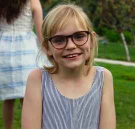 Child wearing glasses and smiling.