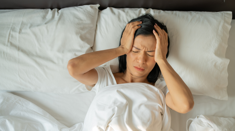 Woman in bed suffering from post traumatic headache.