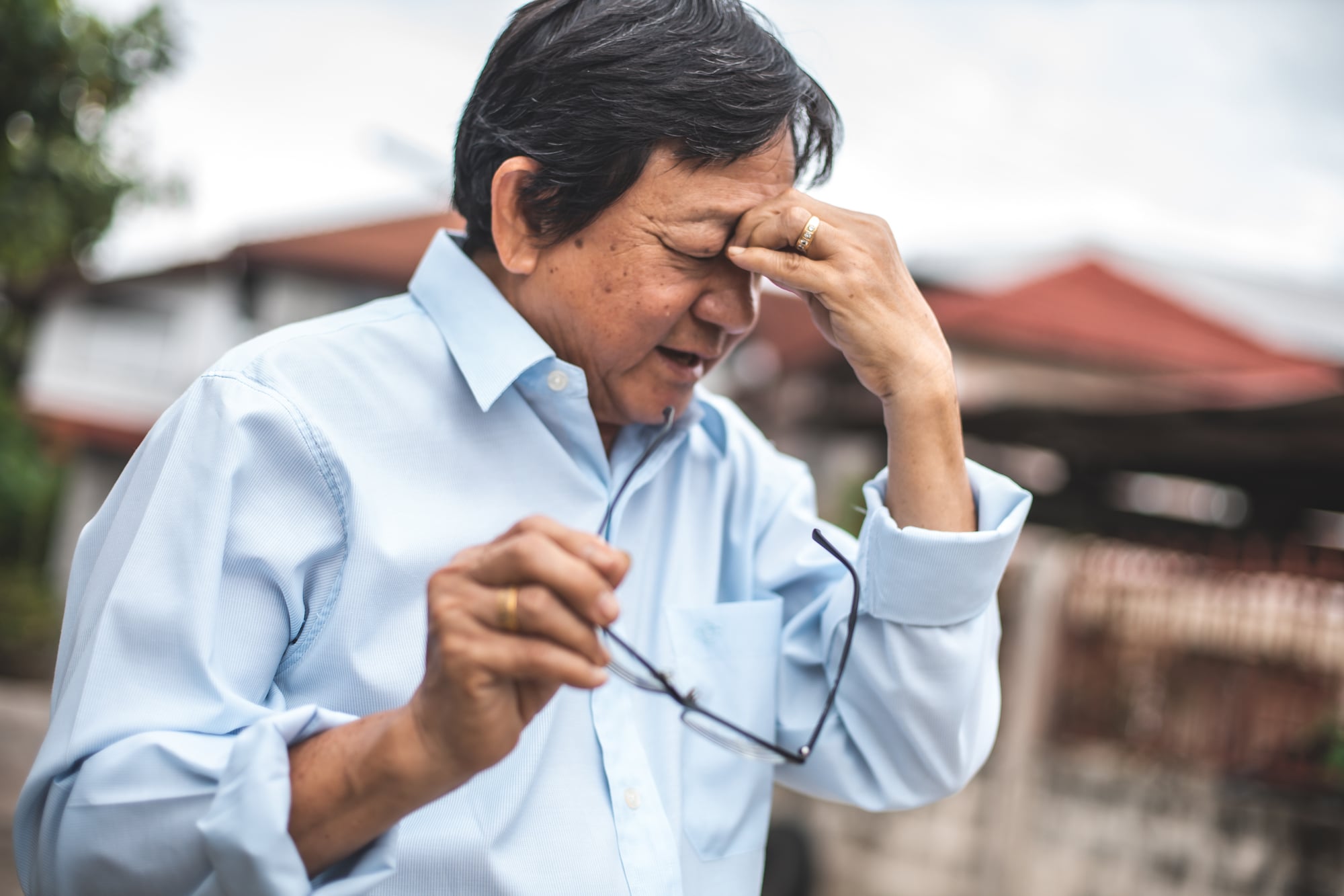 Portrait of an elderly man with headache.Asian elderly stress tired and holding his nose suffer sinus pain fatigue from hard work.