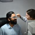 Smiling Indian male checking eye vision with ophthalmologist in